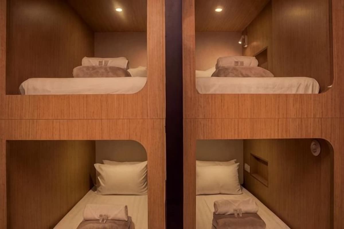 A room with bunk beds, wooden walls, and a small window.