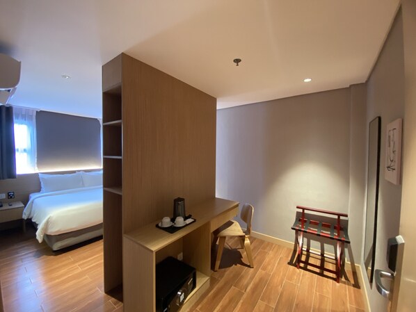 A modern hotel room with a bed, a desk with a chair, a small table, and a TV mounted on the wall. - Moonstar Cebu Hotel (Cebu City)