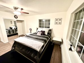 A bedroom with a bed, a bedside table, a lamp, a window, and a ceiling fan. - Family friendly, centrally located home with a pool! (Wasilla)