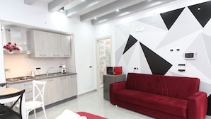 Eine moderne Küche mit hellen Holzschränken, einem roten Sofa und einem Essbereich mit einem weißen Tisch und Stühlen.