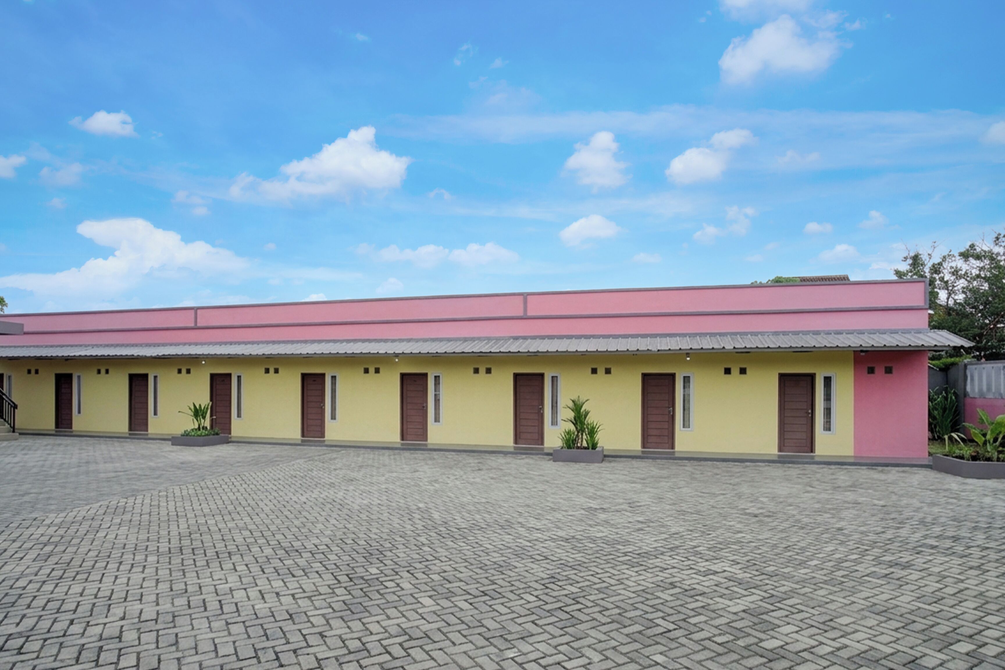 A building with a flat roof, multiple doors, and a paved courtyard.