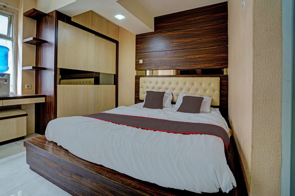 A modern bedroom with a large bed, built-in shelving, and a wooden headboard.
