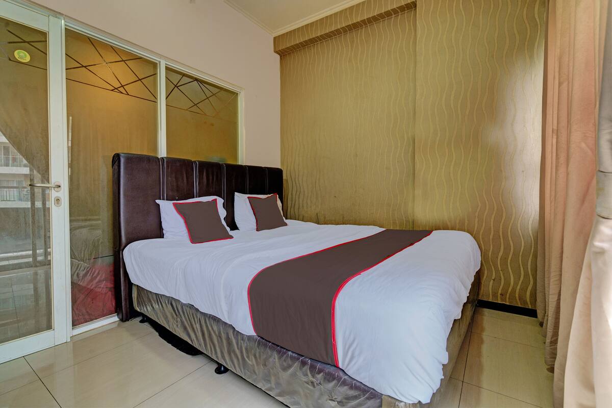 A hotel room with a bed, a sliding glass door, and a curtain.
