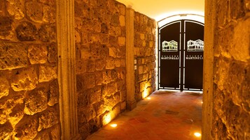 Un corredor de piedra que lleva a una entrada portonada con letreros iluminados que dicen "Palazzo Martinelli".