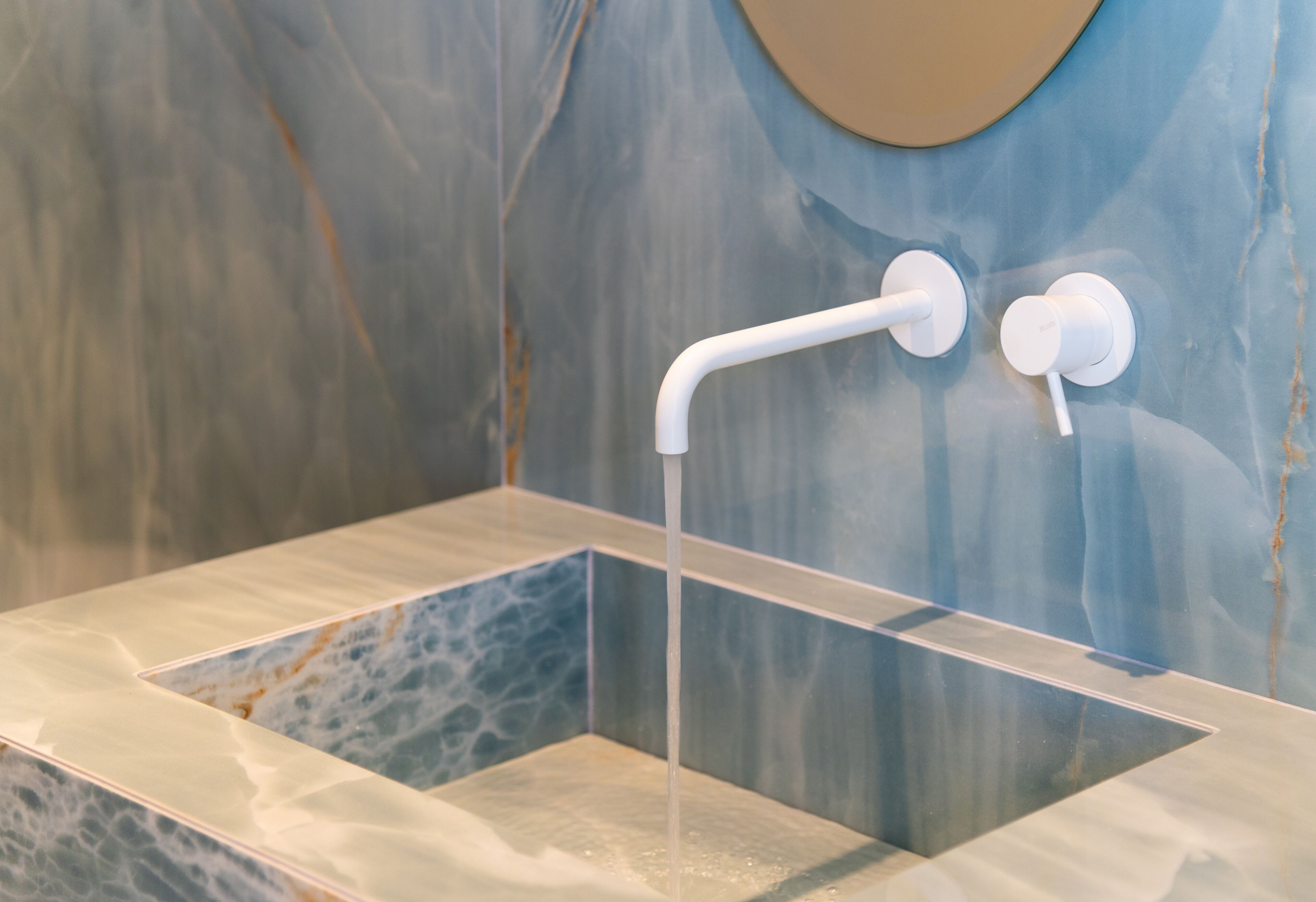 A modern bathroom with a glass-enclosed shower and a marble wall.