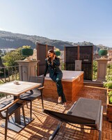 Una terraza con mesa y sillas de madera, un jacuzzi y vistas a una ladera.