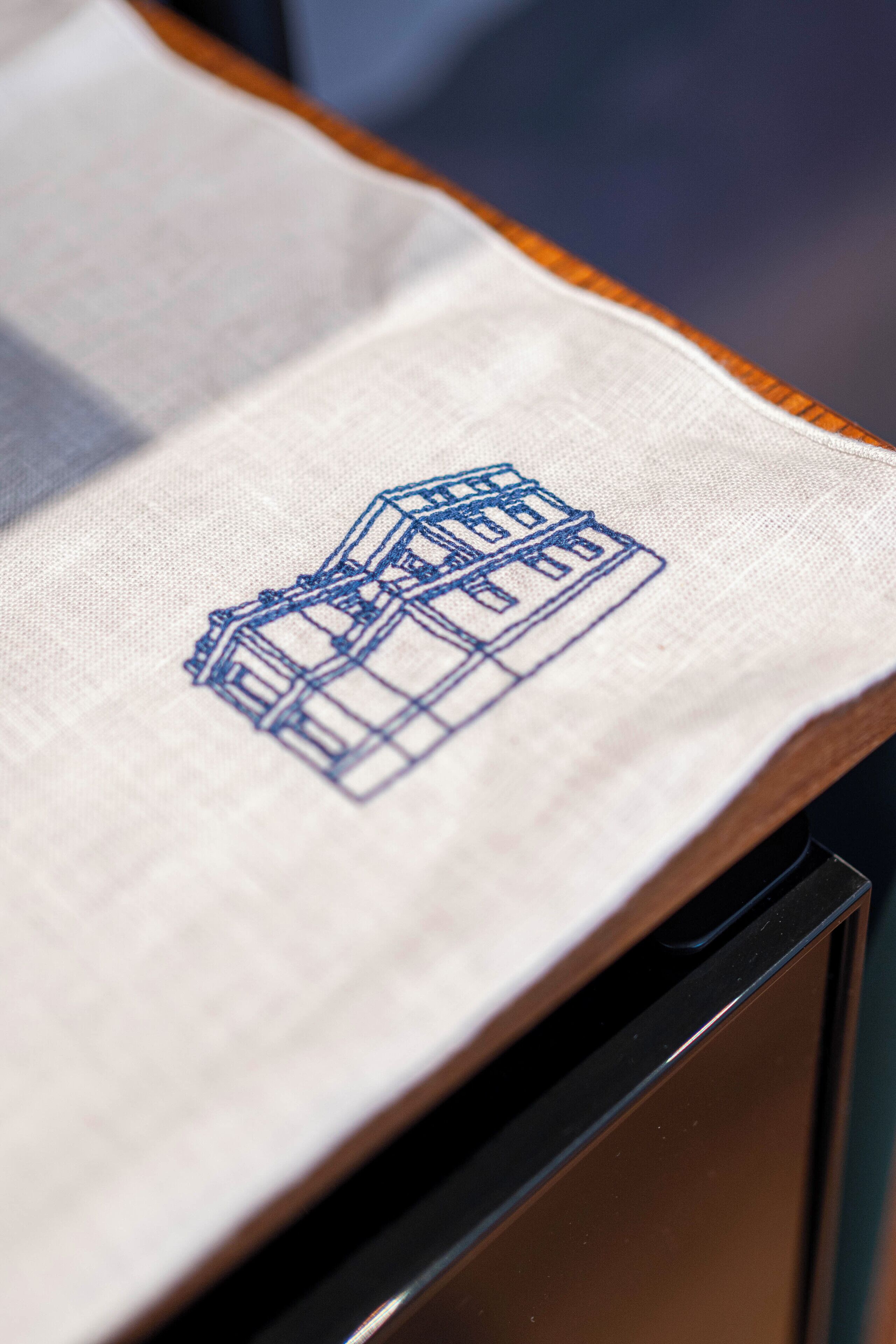 A close-up of a fabric with a blue embroidered building design.