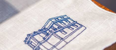 A close-up of a fabric with a blue embroidered building design.