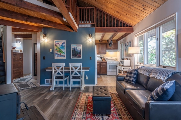 A spacious living area with a dining table, a sofa, and a kitchen in the background.