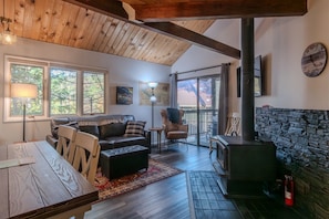A cozy interior with a wooden ceiling, a fireplace, a dining table, and a sofa.