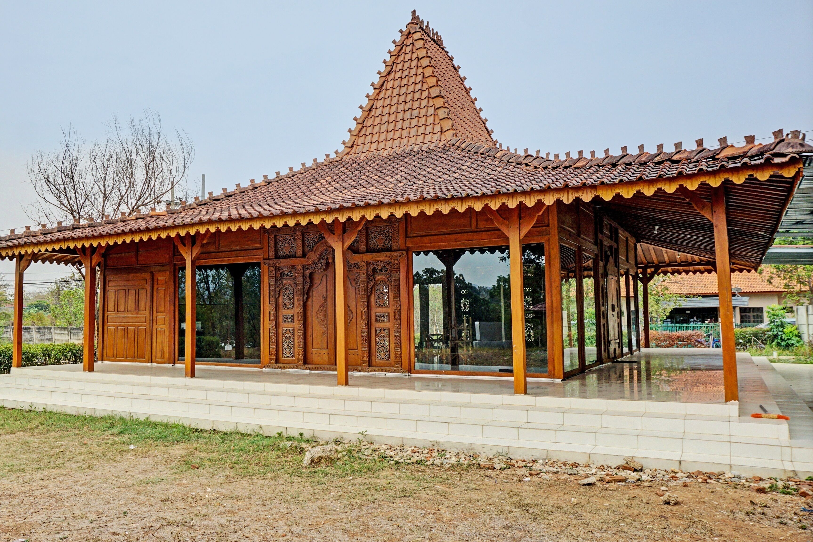 A traditional wooden pavilion with a tiled roof and glass doors.