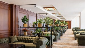 A hotel lobby with a row of green upholstered sofas, a wooden panel wall, and a ceiling with skylights. - Eighty Eight Hotel and Spa (Tsaghkadzor)