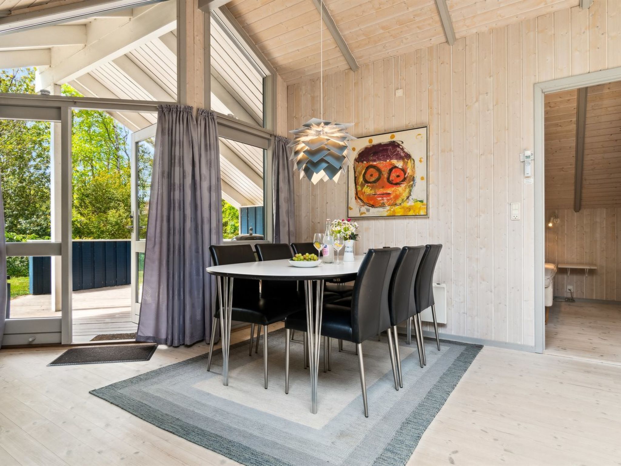 A modern dining area with a round table, black chairs, and a decorative light fixture.