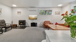 Un salon chaleureux avec une cheminée, des fauteuils en cuir, une table en bois et une grande fenêtre donnant sur un vitrail.