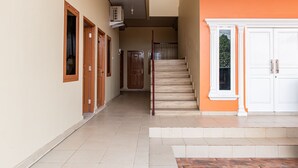 A hallway with wooden doors, a staircase, and a white door at the end. - Hotel O Alnasya Syariah (Palembang)