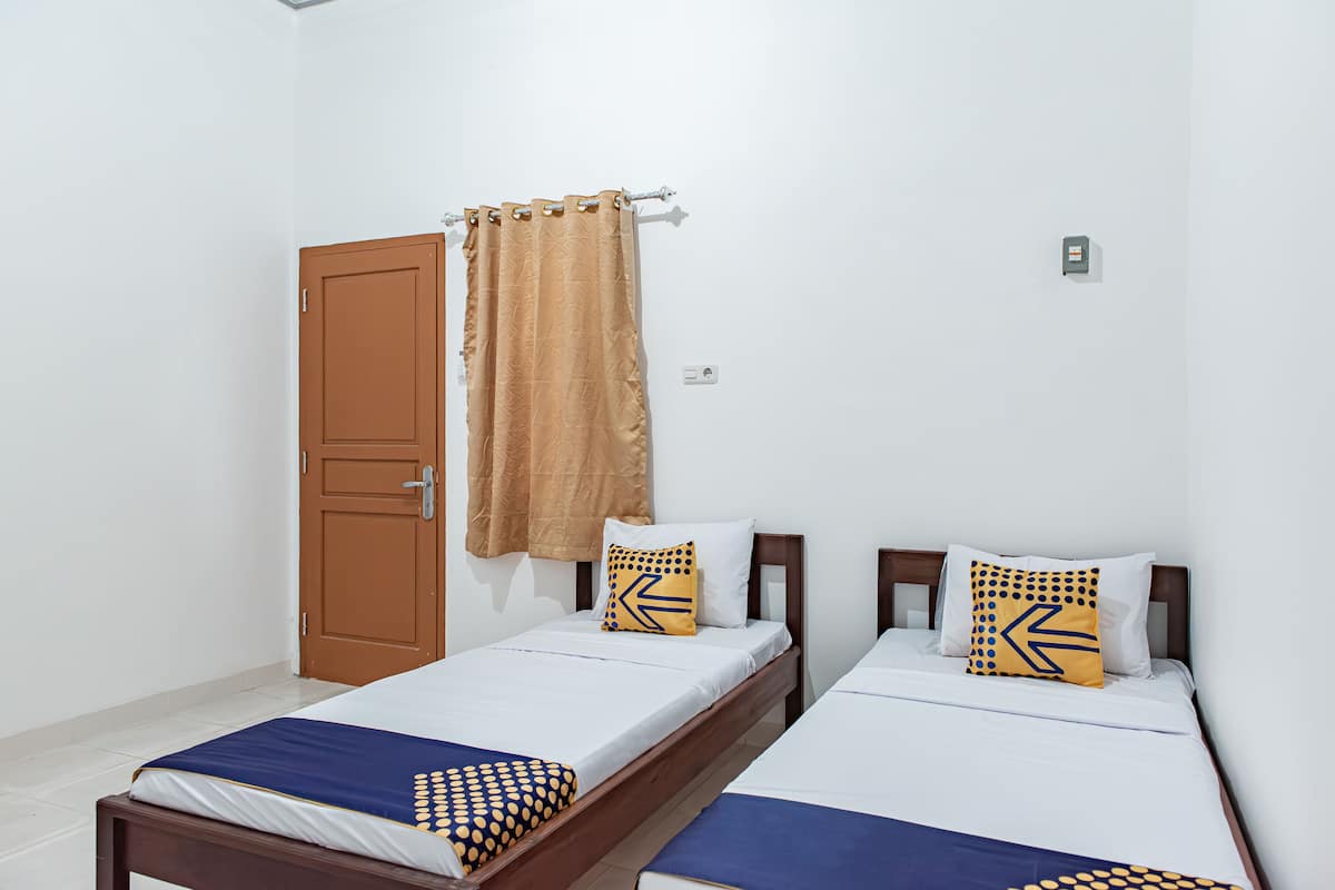 A room with two single beds, a wooden door, and a curtain.