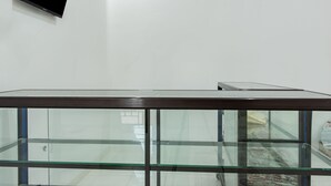 A modern room with a glass partition, a mounted flat-screen TV, and a wooden table. - Hotel O Alnasya Syariah (Palembang)