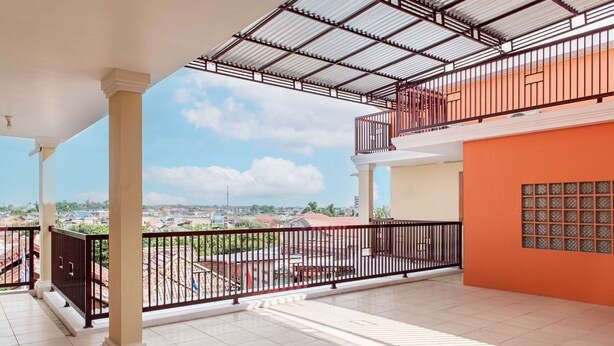 A spacious balcony with a view of the cityscape, featuring a tiled floor and a metal railing. - Hotel O Alnasya Syariah (Palembang)