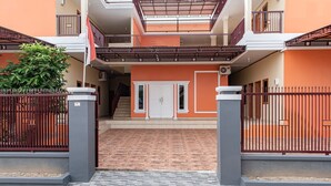 A multi-level residential building with a central staircase, a gated entrance, and a tiled patio area. - Hotel O Alnasya Syariah (Palembang)