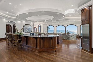 A spacious kitchen with a central island, wooden cabinetry, and large windows offering ocean views.