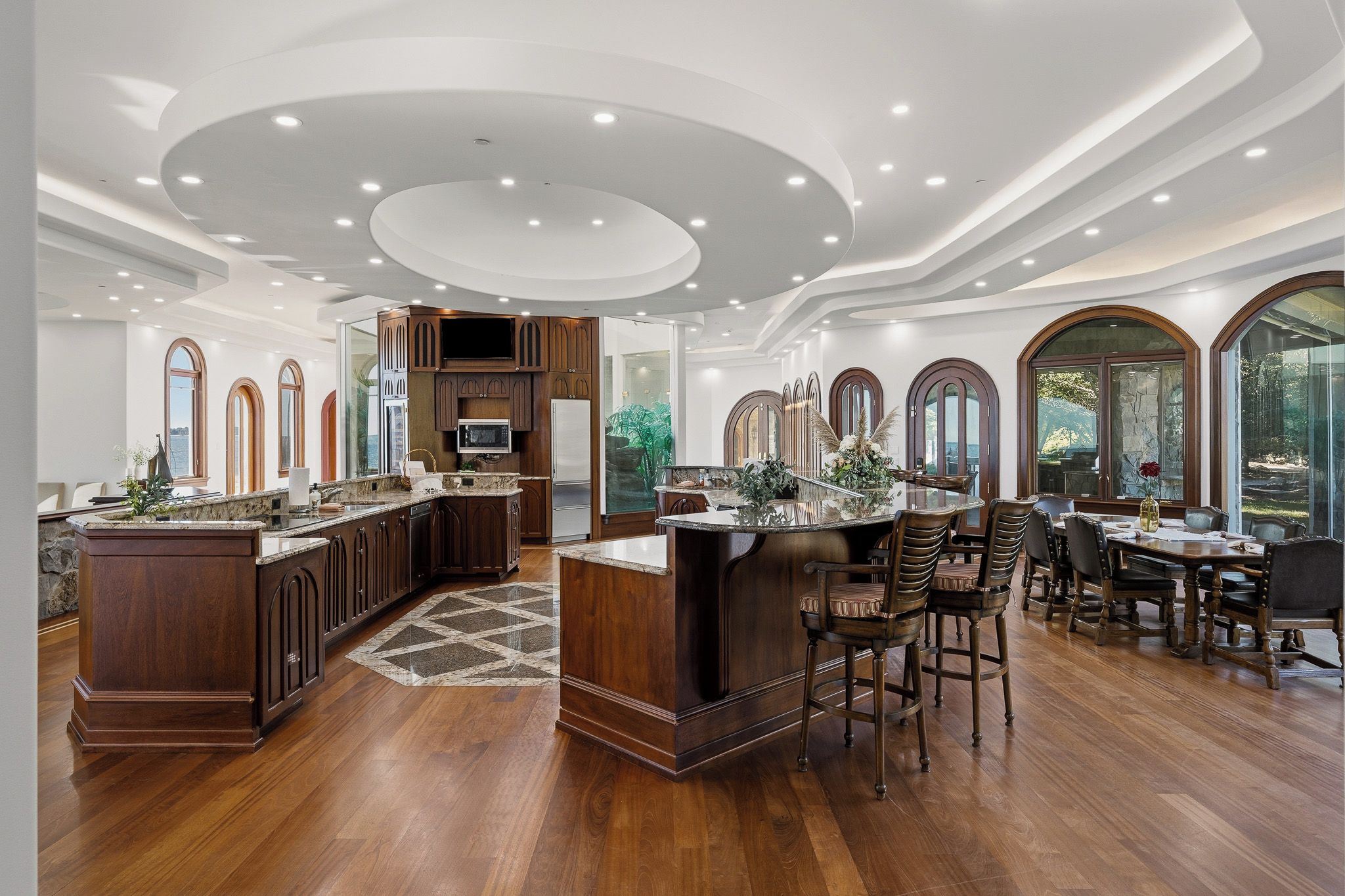 A spacious kitchen with a large island, wooden cabinetry, and a dining area with a table and chairs.