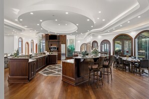 A spacious kitchen with a large island, wooden cabinetry, and a dining area with a table and chairs.