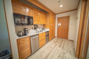 A compact kitchen with wooden cabinets, stainless steel appliances, and a dishwasher.
