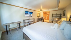A hotel room with a large bed, a desk, a chair, a TV, and a ceiling fan. - Slopeside 2753a (Keystone)