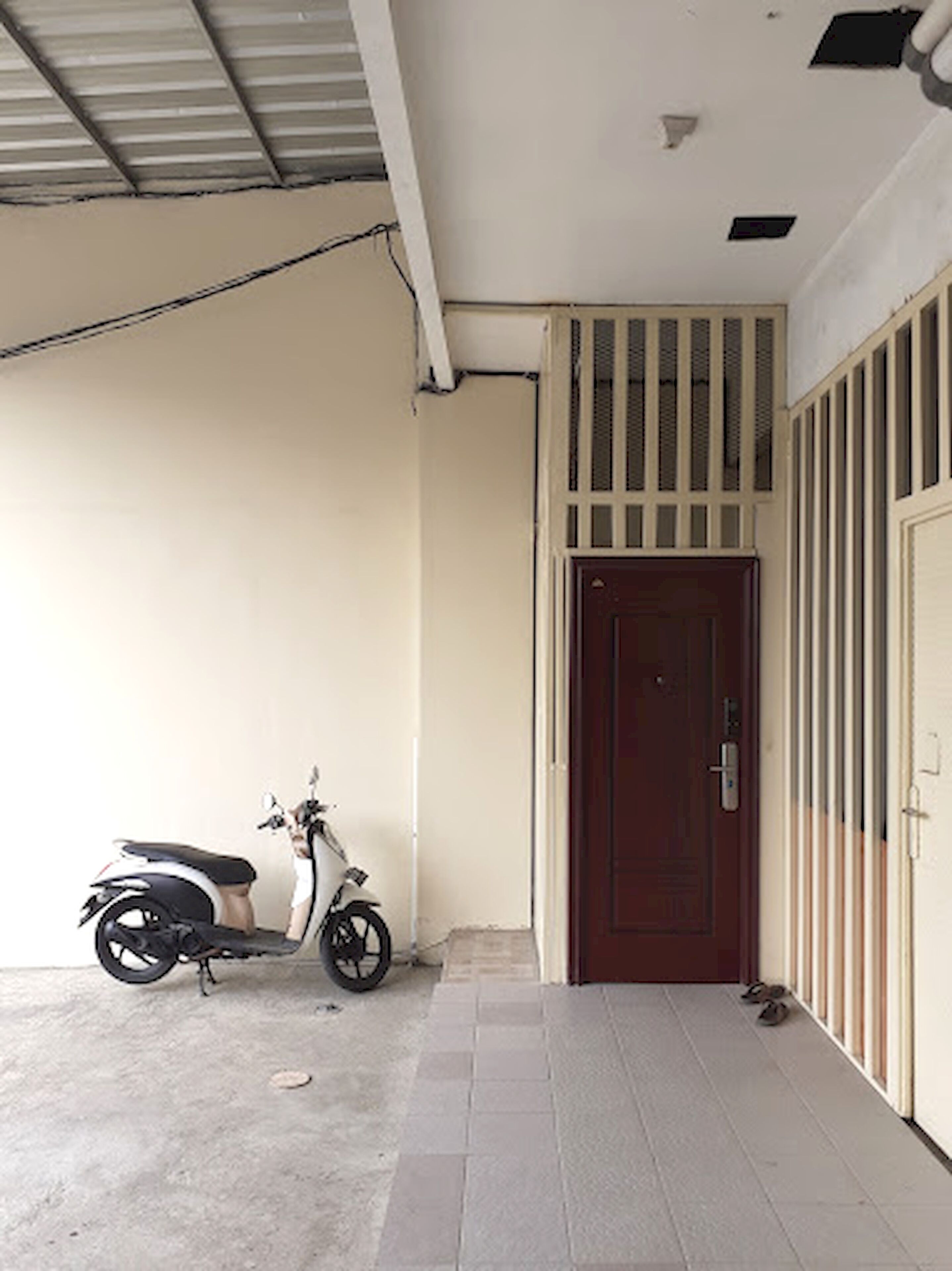 A covered outdoor area with a scooter parked near a door.