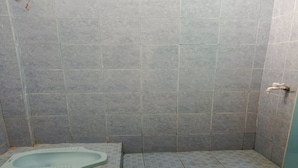 Une petite salle de bain carrelée, avec des toilettes à la turque et un espace douche.