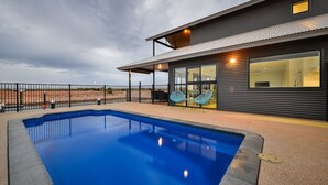 Un edificio moderno con piscina, amplias ventanas y un patio cubierto.