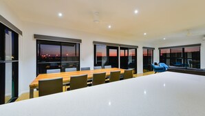 Un salón de conferencias con una larga mesa, sillas y ventanas amplias con vistas a la ciudad.