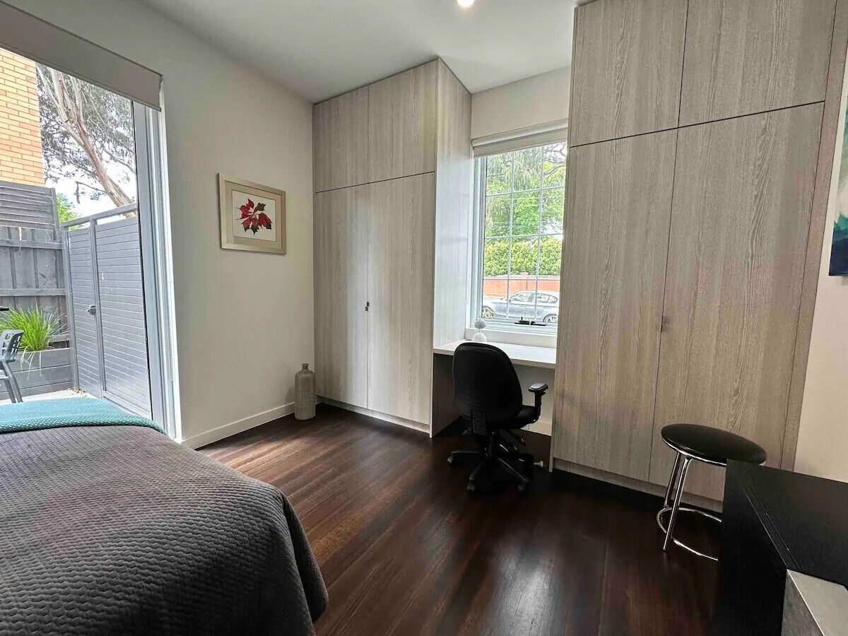 Un dormitorio con cama, escritorio y silla. Se observa una ventana con vista al exterior.