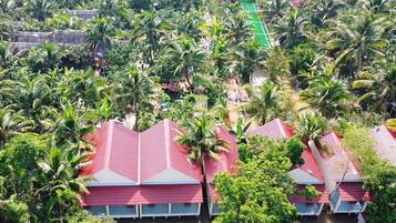 A cluster of red-roofed buildings surrounded by lush greenery and palm trees, indicating a tropical resort setting.