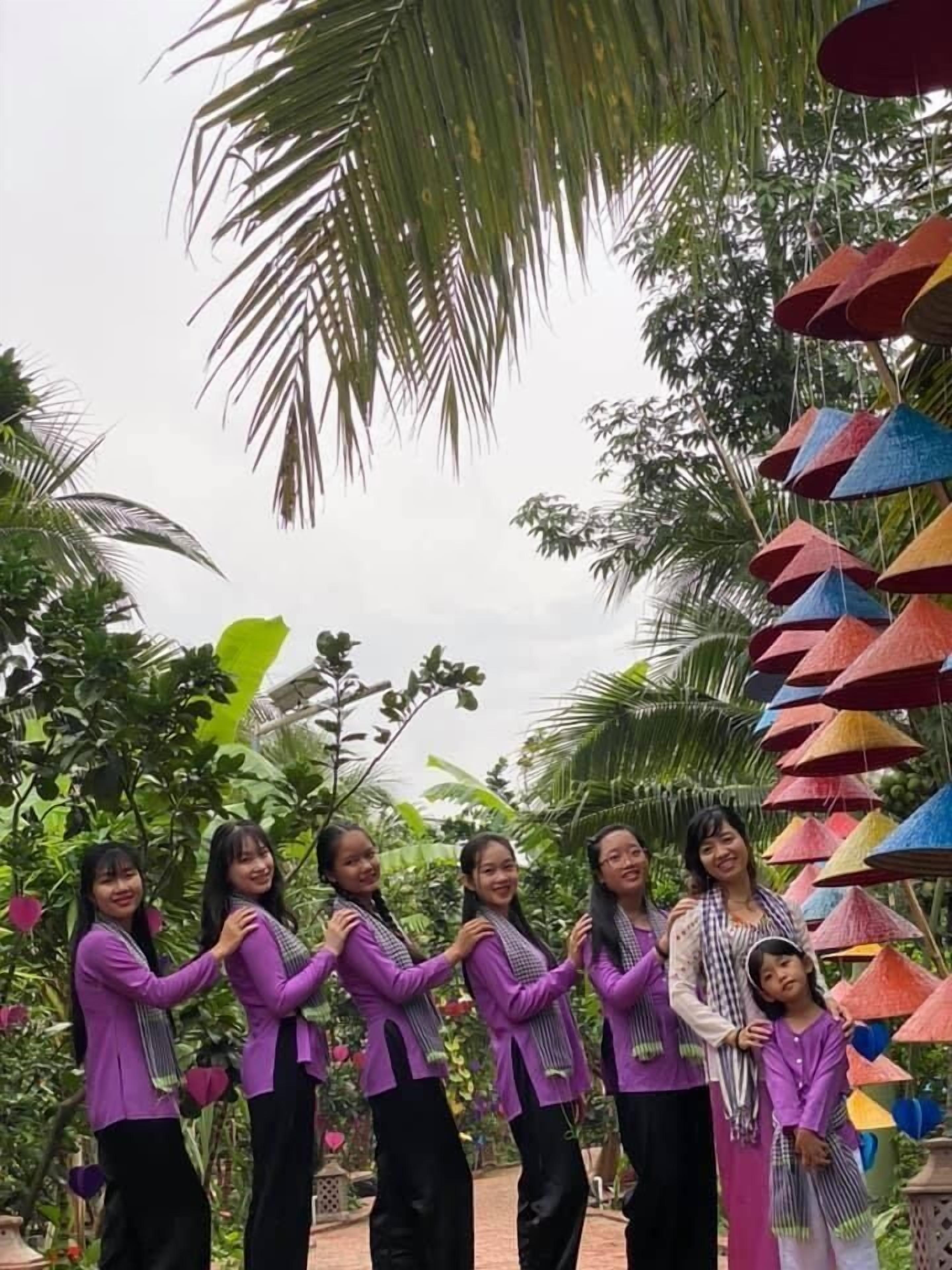 A group of people standing in a garden with palm trees and colorful conical structures.