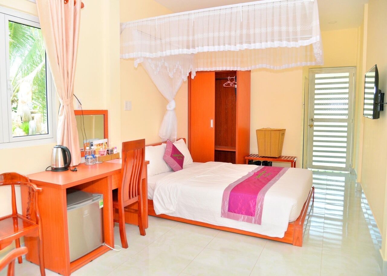 Un dormitorio con cama, escritorio, silla y un refrigerador pequeño.