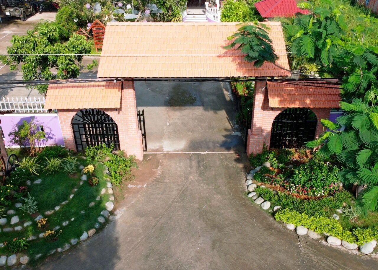 A gated entrance with a concrete pathway leading to a building with a tiled roof.