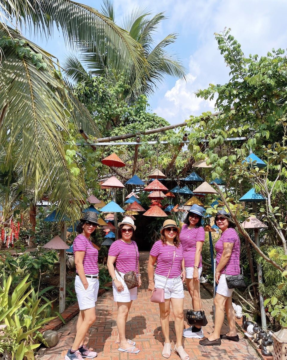 Un grupo de personas de pie en un jardín con un sendero de ladrillos y varios paraguas.