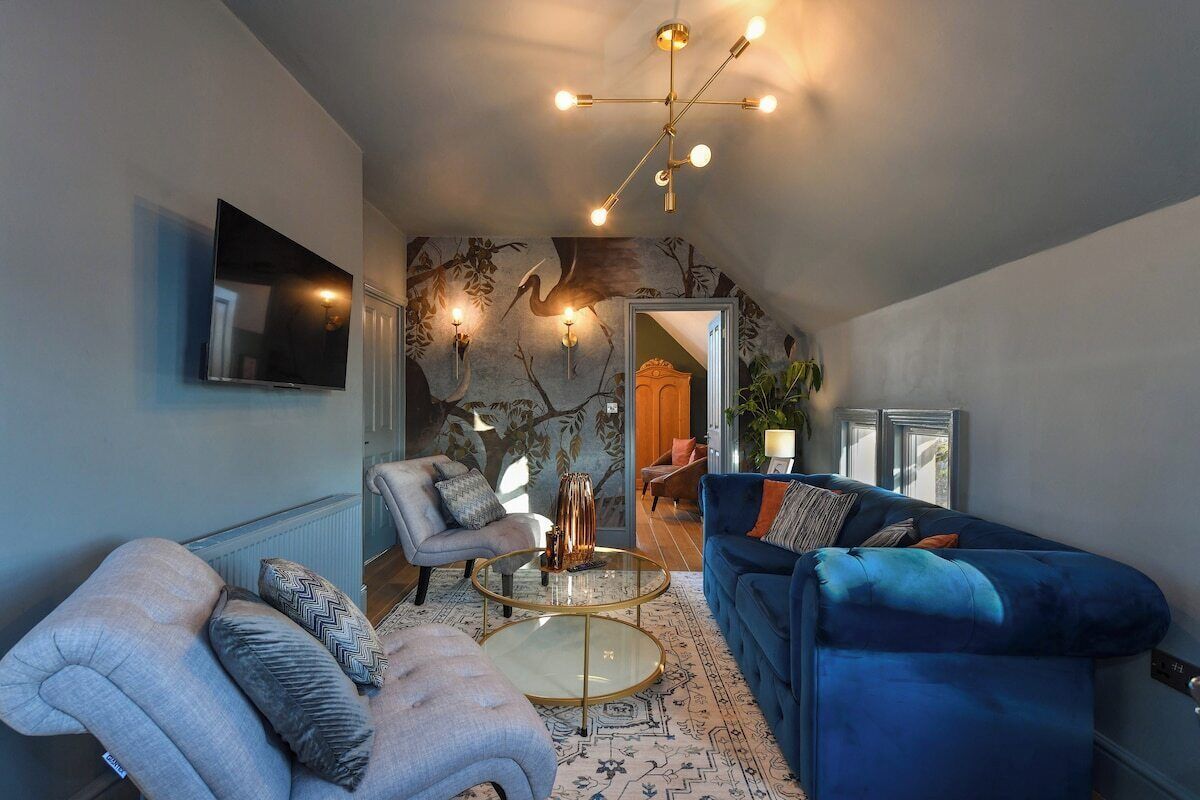 Ein modernes Wohnzimmer mit einem blauen Sofa, grauen Sesseln und einem Glastisch.