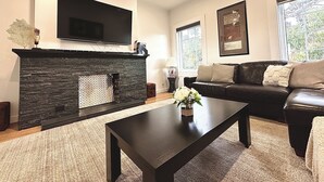 A living room with a fireplace, a sofa, a coffee table, and a TV mounted on the wall. - Luxury & Grandeur | Balcony Views| Prime Location, Parking (Hawthorn)