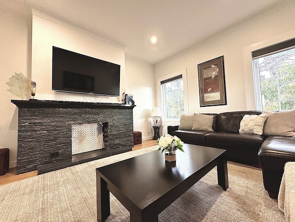 A living room with a fireplace, a sofa, a coffee table, and a TV mounted on the wall.