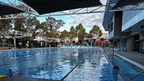 A swimming pool with lane dividers, a lifeguard tower, and a shaded area. - Luxury & Grandeur | Balcony Views| Prime Location, Parking (Hawthorn)