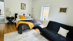 A modern bedroom with a bed, a black sofa, a small table, and a window. - Luxury & Grandeur | Balcony Views| Prime Location, Parking (Hawthorn)