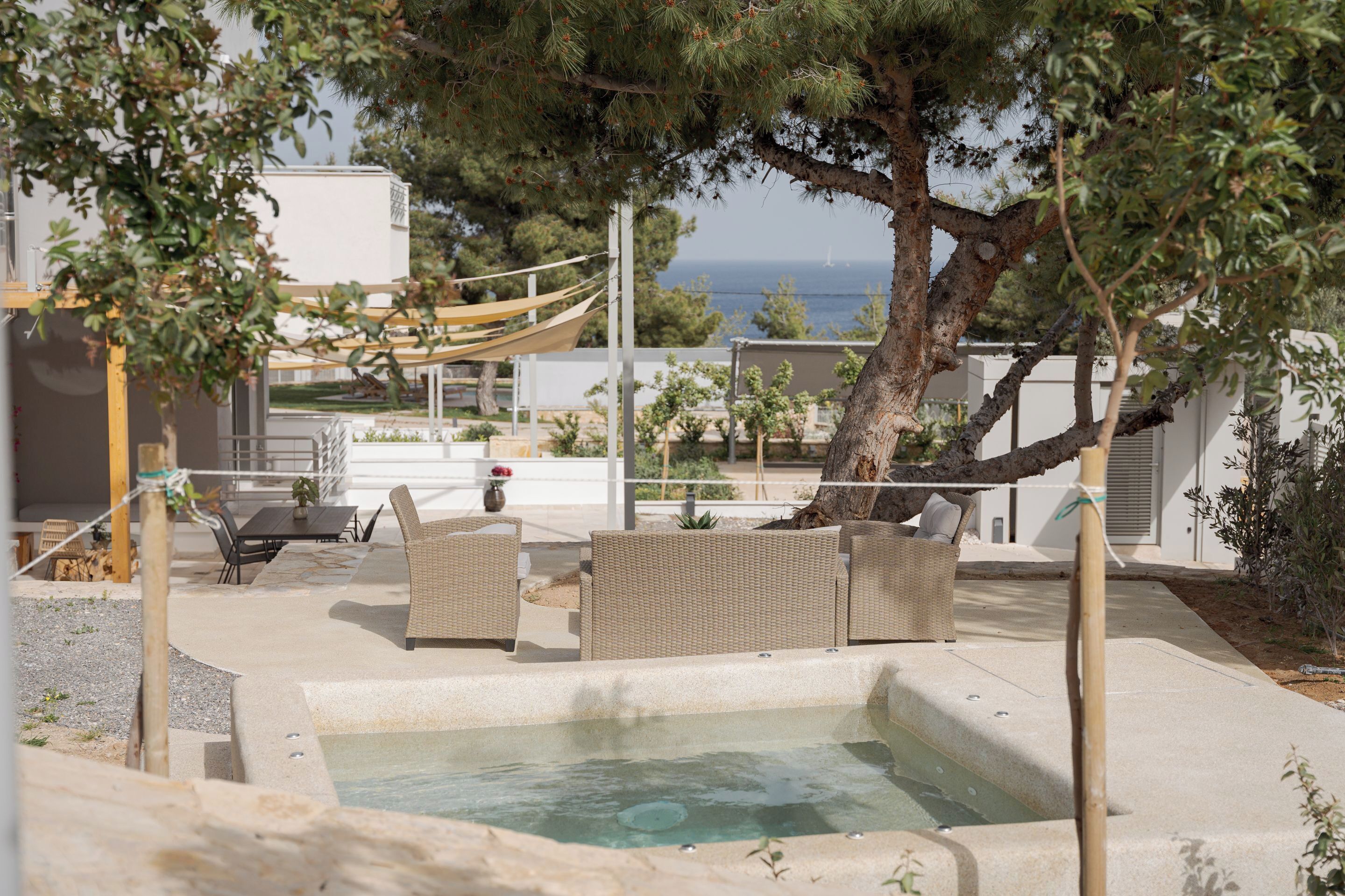 Un espace piscine aménagé avec des meubles en osier et offrant une vue sur la mer.
