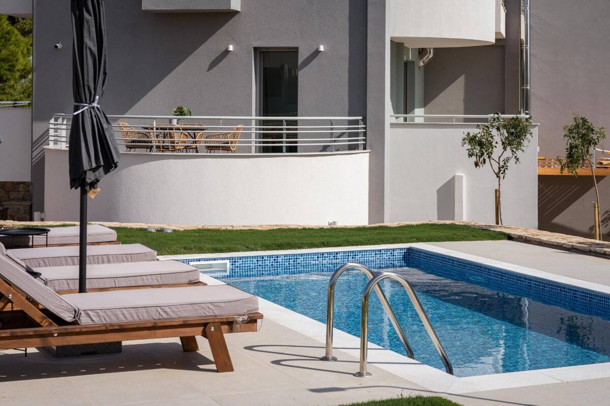A modern pool area with lounge chairs, a pool, and a small deck.