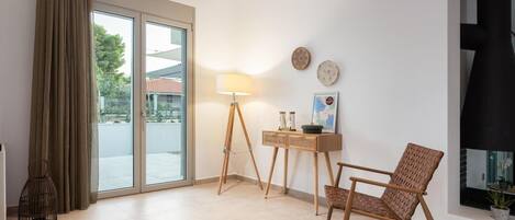 Una sala de estar moderna con un ventanal corredero, una lámpara de pie, una mesita de madera y un sillón de mimbre.