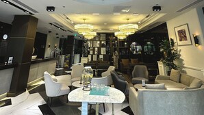 Un vestíbulo de hotel con piso de mármol, zona de estar y mostrador de recepción.