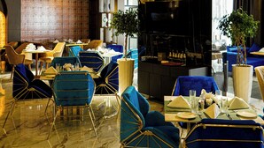 Ein Restaurant mit blau gepolsterten Stühlen, einem Marmorboden und aufwändigen Deckenverzierungen.