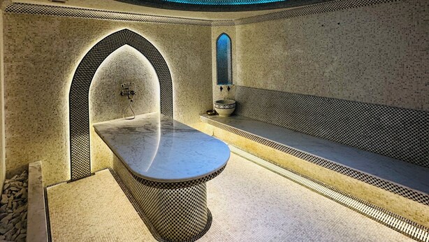 Un baño moderno con un diseño de techo original, un banco y un lavamanos.