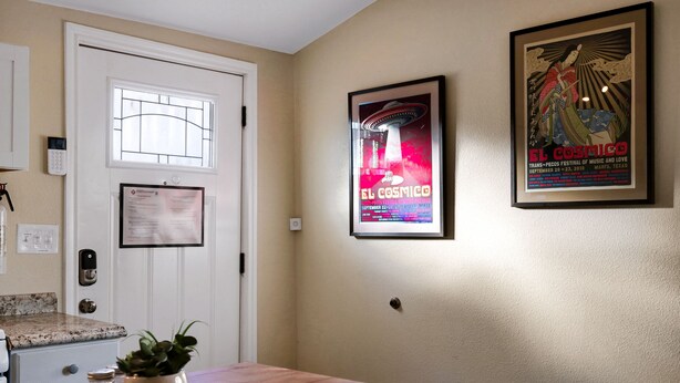 A kitchen with a wooden table, a potted plant, and a poster on the wall.